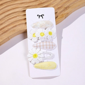 Detailed close-up of five-piece hair clip set with daisy and floral embroidery on card