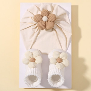 Detailansicht der cremefarbenen Babymütze und passenden Socken mit Cordblumen-Dekor