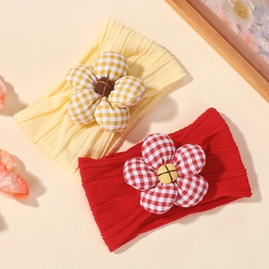 Detailed macro view of yellow and red ribbed baby headbands with large plaid floral bows