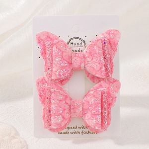 Détail de pinces à cheveux papillon en dentelle rose et paillettes sur carte