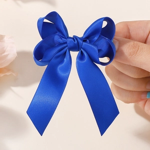 Detail showing high-quality royal blue double-layer satin ribbon bow hair clip on hand