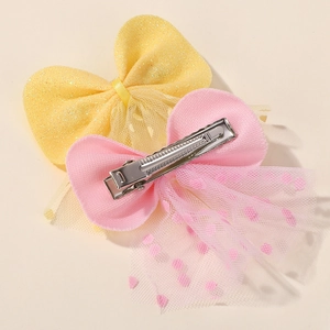 Detail of pink polka dot mesh bow hair clip featuring a secure silver metal duckbill clip
