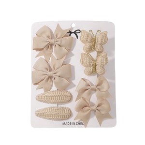 Detail view of 8-piece beige hair clip set with ribbon bows and knitted textures