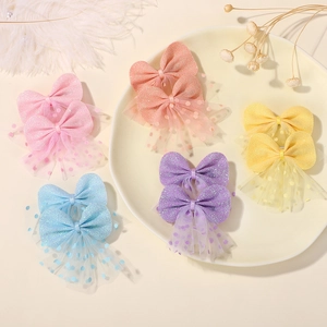 Detailed view of layered mesh bow hair clips in five colors on a decorative tray
