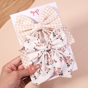 Détail de deux grandes barrettes nœuds avec motifs à carreaux marguerite et fleurs