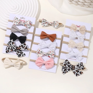 Flat lay of diverse baby bow headbands featuring floral, lace, and leopard print designs