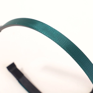 Close-up of deep green grosgrain ribbon texture and protective tip on kids headband