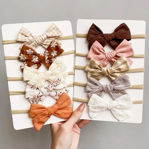 Detail of 10-piece baby bow headband set in various fabrics like lace, floral, and solid linen