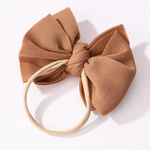 Détail d'un nœud papillon marron en tricot texturé avec un élastique nude sans couture