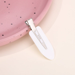 Detail view of a minimalist white hair clip on a pink decorative plate for hairstyling