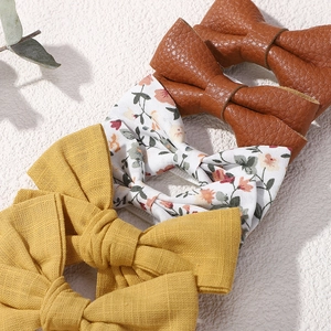Gros plan de barrettes à cheveux en tissu floral et cuir avec des détails texturés