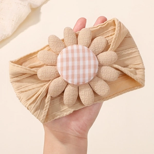Détail du bandeau bébé beige avec une grande tournesol et une maille en nylon souple