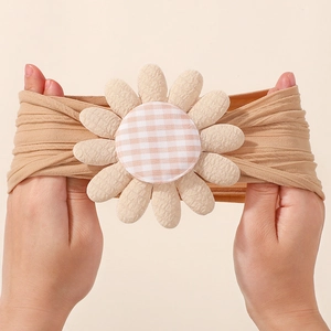 Détail de la grande élasticité du bandeau doux pour bébé avec décoration de marguerite