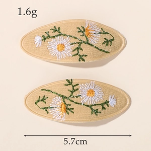 Vue détaillée des barrettes ovales en tissu beige avec broderie marguerite de 5,7 cm