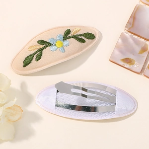 Détails de barrettes brodées à fleurs montrant le tissu et le clip en métal