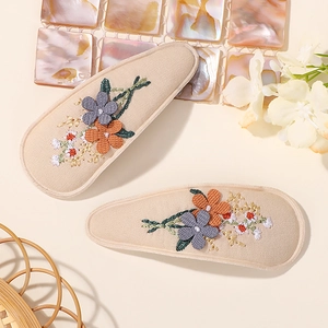 Gros plan sur deux barrettes en tissu beige avec broderie florale délicate pour filles