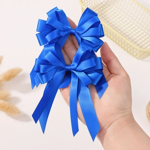 Détail de pinces à cheveux en satin bleu roi avec nœuds superposés et longs rubans fluides