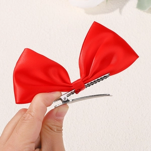 Close-up of a red satin ribbon hair clip featuring a durable silver metal alligator clip