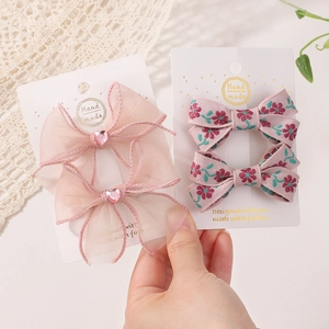 Details von rosa Organza- und Stoff-Haarspangen mit floralem Muster und Herzsteinen
