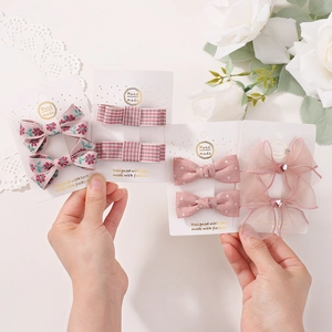 Detail von rosa Schleifen-Haarspangen-Set mit Blumenmuster und glitzernden Herzsteinen
