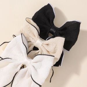 Detail view of fabric bow hair clips with contrast piping and crinkled texture