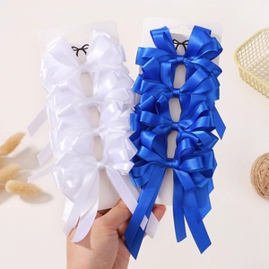 Détail de pinces à nœuds en ruban de satin double épaisseur avec longs rubans pendants