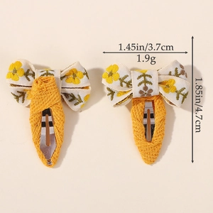Set of two yellow embroidered floral bow hair clips with stable fabric wrapped BB clips