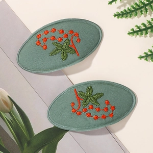 Paire de barrettes à cheveux ovales en tissu vert sauge avec motifs d'étoiles brodées