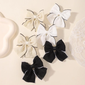 Detail of 6-piece bow hair clips set showing textured fabric and contrast edge stitching