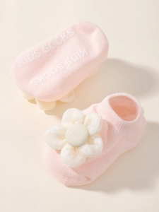 Détail de chaussettes bébé en tricot rose avec fleurs en tissu et semelles antidérapantes