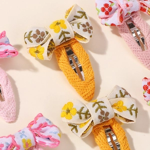 Close-up of floral embroidery fabric bows on fabric-wrapped safety hair clips