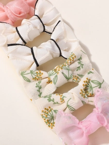Close-up of four assorted handmade bow hair clips in satin, floral cotton, and organza