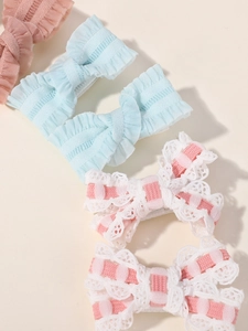 Detailed close-up of handmade embroidered lace and satin ribbon bow hair clips for girls