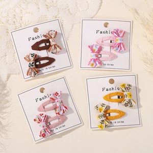 Detail showing embroidered floral bows and knitted fabric hair clips on display cards