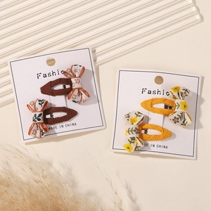 Detail of handmade fabric bow hair clips with floral embroidery on white display cards