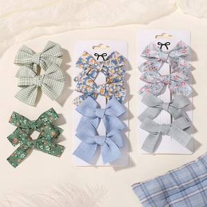 Close-up of fabric bow hair clips with floral and plaid patterns on display card