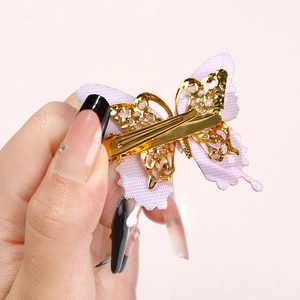 Close-up of golden butterfly hair clip with purple fabric and metal duckbill back