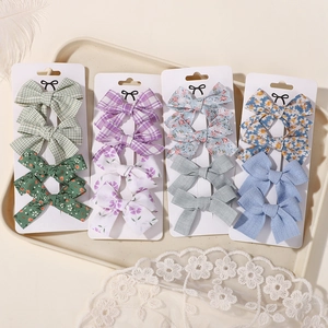 Detailed close-up of 16-piece fabric bow hair clips set on display cards