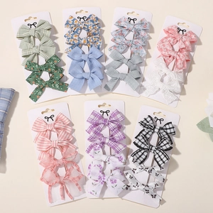 7 sets of 4-piece bow hair clip sets for kids featuring assorted floral and plaid fabric styles