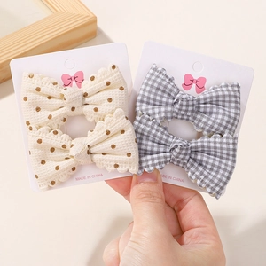 Dettaglio ravvicinato di fermagli per capelli con fiocchi beige a pois e a quadri grigi