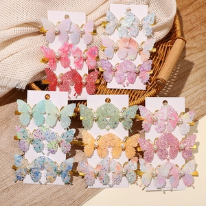 Colorful glitter butterfly hair clips for girls featuring faux pearl accents and gold base