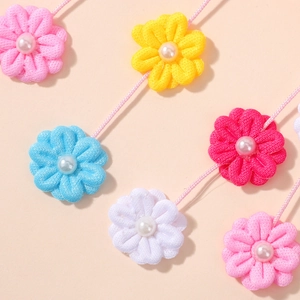 Détail de barrettes fleurs en tissu coloré avec perles et longs glands pour filles