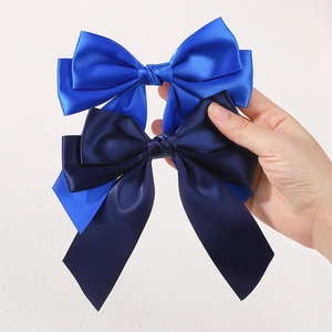 Detailed macro view of large silk satin hair bows in royal blue and navy blue fabric