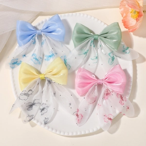 Détail de quatre barrettes à nœuds en tulle coloré avec fleurs et strass brillants