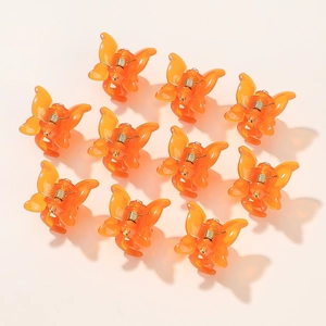 Set of 10 mini orange butterfly hair clips with matte finish on a pink background