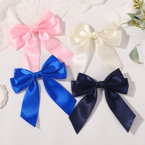Four colorful satin bow hair clips for girls in pink, cream, royal blue, and navy colors