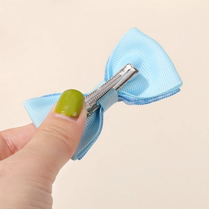 Dettaglio del fiocco in nastro grosgrain azzurro con clip a coccodrillo in metallo