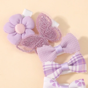 Detail of five handmade purple hair clips featuring floral embroidery and plaid patterns