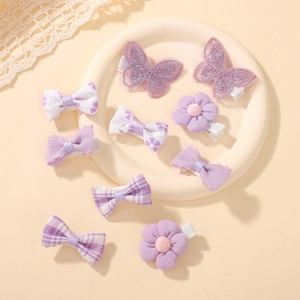 Flat lay of 10 purple fabric hair clips including lace butterfly and floral bow styles