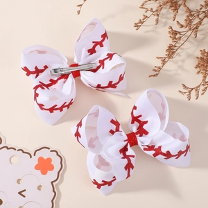 Detail of white grosgrain hair clips with red glitter baseball stitching and metal clips
